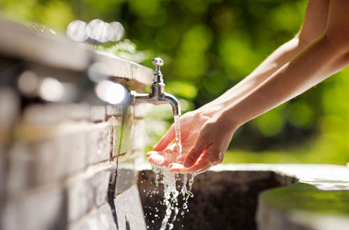person washing hands in faucet person washing hands in faucet